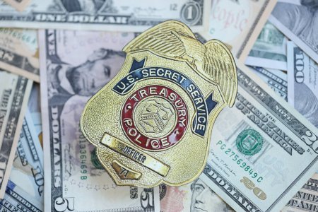 Foto de KYIV, UCRANIA - 9 de marzo de 2024 La insignia del oficial del Servicio Secreto de la Policía del Tesoro estadounidense en muchos billetes de dólar estadounidense se cierra - Imagen libre de derechos