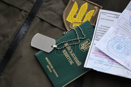 Boleto de identificación militar o militar con aviso de movilización se encuentra en uniforme militar ucraniano verde en el interior de cerca