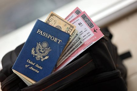 Blauer Reisepass der Vereinigten Staaten von Amerika mit Geld und Flugtickets auf Touristenrucksack aus nächster Nähe. Tourismus- und Reisekonzept