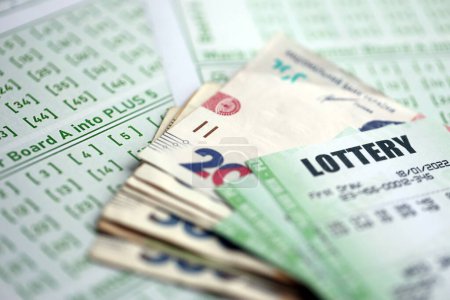 Grüne Lotterielose und ukrainische Geldscheine auf blankem Papier mit Zahlen für das Lotteriespiel aus nächster Nähe