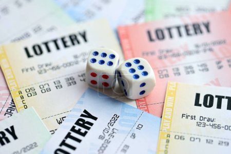 Viele Lottoscheine und Würfel auf leeren Scheinen mit Zahlen zum Lotteriespiel aus nächster Nähe
