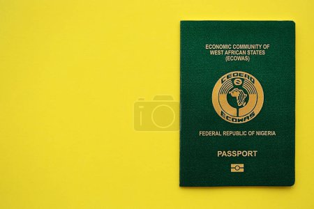 Green Nigerian passport on yellow background close up. Tourism and citizenship concept