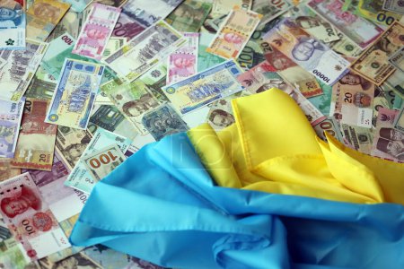 Ukrainische Flagge auf vielen Banknoten verschiedener Währung. Hintergrund der Kriegsfinanzierung und des Preises für militärische Unterstützung in der Ukraine
