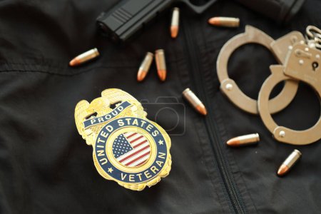 Téléchargez les photos : KYIV, UKRAINE - 9 MARS 2024 US Fiers insigne d'ancien combattant sur un uniforme veste noire avec pistolet, balles et menottes près - en image libre de droit
