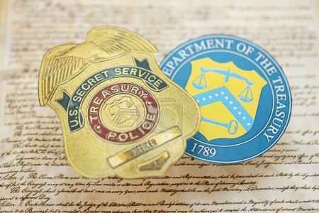 Foto de KYIV, UCRANIA - 9 de marzo de 2024 La insignia del oficial del Servicio Secreto de la Policía del Tesoro de Estados Unidos y el sello del Departamento del Tesoro sobre la Constitución de Estados Unidos se cierran - Imagen libre de derechos