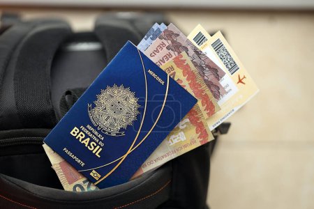 Passeport brésilien bleu avec de l'argent et des billets d'avion sur le sac à dos touristique de près. Tourisme et concept de voyage