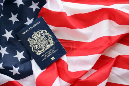 Pasaporte británico azul en el fondo de la bandera nacional de Estados Unidos de cerca. Concepto de turismo y diplomacia