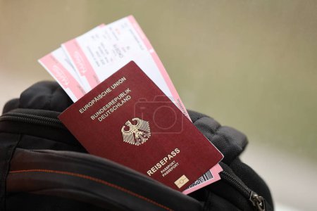 Red German passport of European Union with airline tickets on touristic backpack close up. Tourism and travel concept
