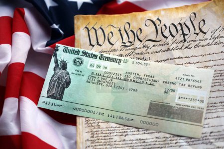 Preámbulo a la Constitución de los Estados Unidos y cheque de reembolso en la bandera americana. Antiguo papel amarillo con texto We The People