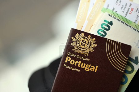 Roter portugiesischer Pass der Europäischen Union mit Geld und Flugtickets auf Touristenrucksack in Großaufnahme. Tourismus- und Reisekonzept