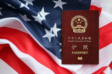 Roter Pass der Volksrepublik China auf der Flagge der Vereinigten Staaten. Chinesischer Pass der Volksrepublik China auf hellem Hintergrund in Nahaufnahme