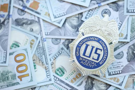 Foto de KYIV, UCRANIA - 9 DE MARZO DE 2024 US DEA Special Agent badge on many US hundred dollar bills close up - Imagen libre de derechos