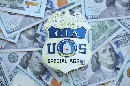 Foto de KYIV, UCRANIA - 9 de marzo de 2024 US CIA Central Intelligence Agency badge on many US hundred dollar bills close up - Imagen libre de derechos