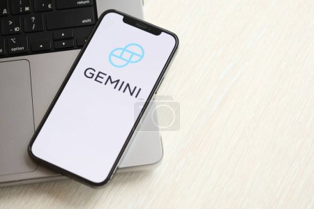 Photo for KYIV, UKRAINE - MARCH 15, 2024 Gemini logo on iPhone display screen on MacBook panel. Cryptocurrency exchange portal logo on iPhone display screen with dollars and bitcoins on MacBook. Cryptocurrency - Royalty Free Image