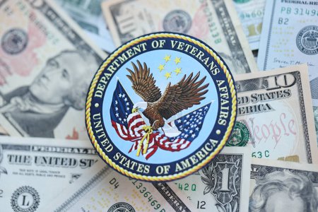 Photo for KYIV, UKRAINE - MARCH 9, 2024 US Department of Veteran Affairs seal on many US dollar bills close up - Royalty Free Image