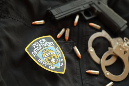 Foto de KYIV, UCRANIA - 9 DE MARZO DE 2024 US NYPD Parche policial en uniforme de chaqueta negra con pistola, balas y esposas de cerca - Imagen libre de derechos