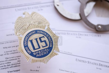Téléchargez les photos : KYIV, UKRAINE - 9 MARS 2024 US DEA Insigne d'agent spécial avec menottes sur de nombreux mandats de la Cour de district des États-Unis et plaintes close up - en image libre de droit