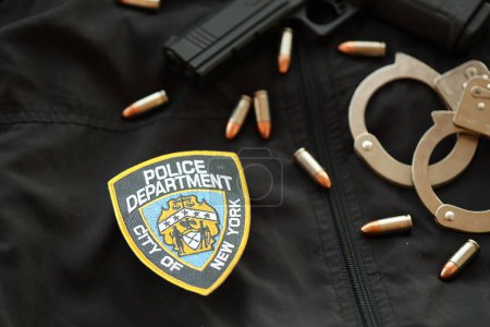 Foto de KYIV, UCRANIA - 9 DE MARZO DE 2024 US NYPD Parche policial en uniforme de chaqueta negra con pistola, balas y esposas de cerca - Imagen libre de derechos