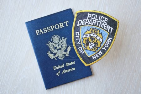 Foto de KYIV, UCRANIA - 9 de marzo de 2024 US NYPD Police patch and United States passport on wooden table close up - Imagen libre de derechos