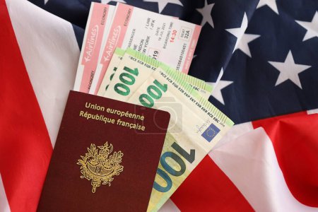 Französischer Pass und Eurogeld mit Flugtickets auf dem Hintergrund der US-Nationalflagge. Tourismus- und Diplomatie-Konzept