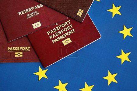 Die Pässe der EU-Länder auf blauer EU-Flagge in Großaufnahme. Portugal, deutscher, französischer und polnischer Pass
