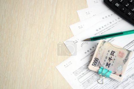Formularios de impuestos japoneses se encuentra en la mesa con calculadora, bolígrafo y billetes de yenes japoneses rollo de cerca