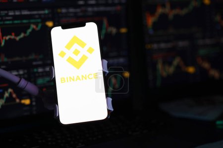 Photo for KYIV, UKRAINE - MARCH 15, 2024 Binance logo on iPhone display screen and crypto currency value charts. Cryptocurrency exchange portal - Royalty Free Image