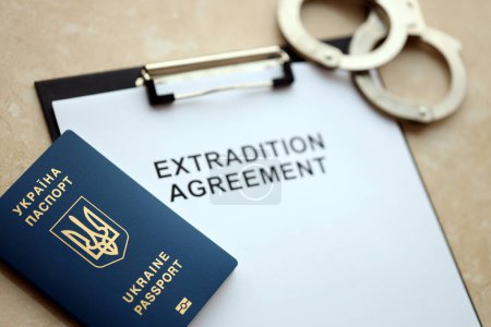 Pasaporte de Ucrania y Acuerdo de Extradición con esposas en la mesa de cerca