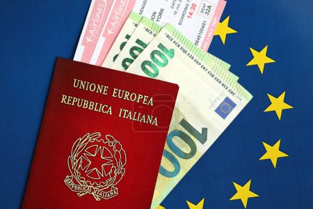 Italienischer Pass der Europäischen Union und Flugtickets auf blauem Flaggenhintergrund in Großaufnahme. Tourismus- und Reisekonzept