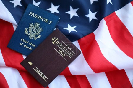 Reisepass der Republik Iran mit US-Pass auf gefalteter Flagge der Vereinigten Staaten von Amerika in Großaufnahme