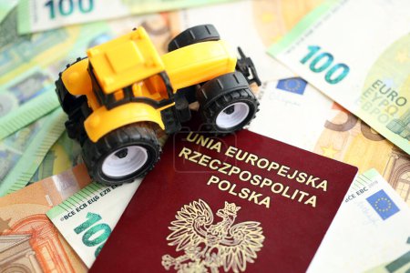 Pasaporte rojo polaco y tractor amarillo en billetes de euros de cerca