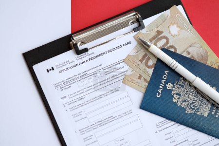 Antrag auf Daueraufenthaltskarte auf dem Tisch mit Stift und kanadischem Pass mit Geld aus nächster Nähe