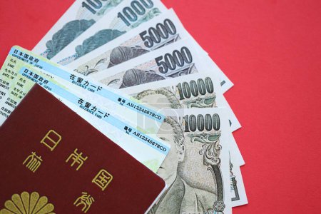 Téléchargez les photos : Carte de séjour verte du Japon avec passeport et argent du yen japonais sur fond rouge gros plan - en image libre de droit