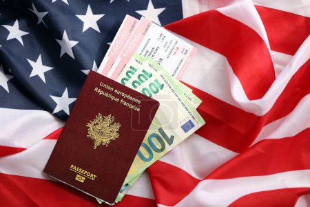Französischer Pass und Eurogeld mit Flugtickets auf dem Hintergrund der US-Nationalflagge. Tourismus- und Diplomatie-Konzept