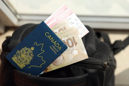 Pasaporte canadiense y billetes de dinero en dólares con billetes de avión en la mochila de cerca