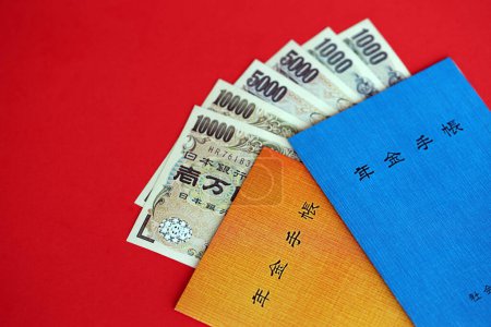 Livrets japonais d'assurance pension sur table avec billets en yen. Livres bleu et orange pour retraités japonais close up