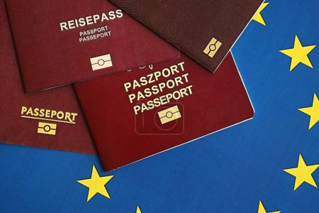 Die Pässe der EU-Länder auf blauer EU-Flagge in Großaufnahme. Portugal, deutscher, französischer und polnischer Pass