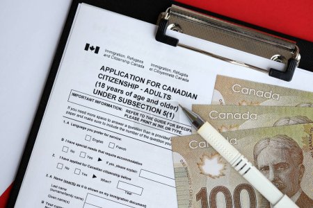 Solicitud de ciudadanía canadiense para adultos en la mesa con bolígrafos y billetes de dólar de cerca