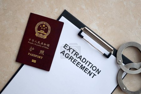 Passport of China Republic and Extradition Agreement with handcuffs on table close up