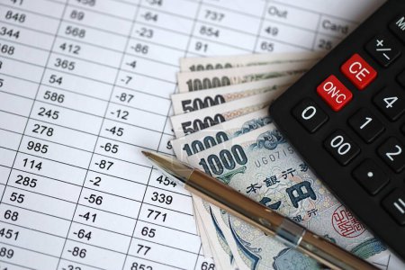 Japanese tax calculations lies on table with calculator, pen and japanese yen money bills close up
