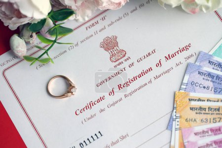 Foto de Certificado indio de registro de matrimonio documento en blanco y anillo de bodas con dinero rupia en la mesa de cerca - Imagen libre de derechos