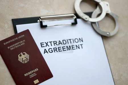 Reisepass Deutschlands und Auslieferungsabkommen mit Handschellen auf dem Tisch