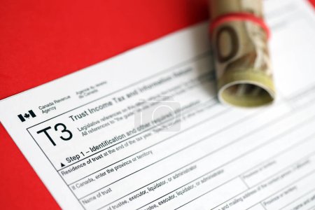 Canadian T3 tax form Trust income tax and information return liegt auf dem Tisch mit kanadischen Geldscheinen in Großaufnahme. Besteuerung und jährliche Buchhaltung in Kanada