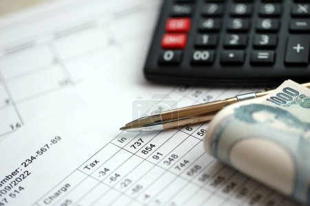 Cálculos de impuestos japoneses se encuentra en la mesa con la calculadora, pluma y billetes de yenes japoneses en primer plano