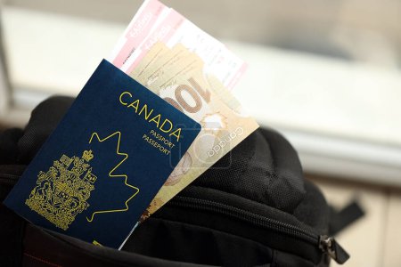 Kanadischer Pass und Dollarscheine mit Flugtickets im Rucksack aus nächster Nähe