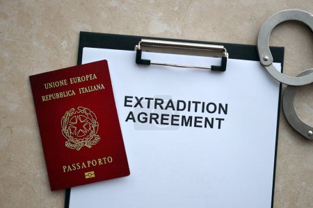 Italienischer Pass und Auslieferungsabkommen mit Handschellen auf dem Tisch