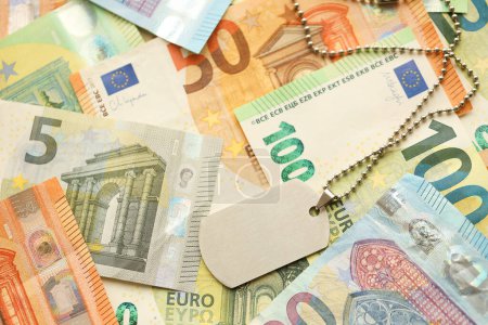 Viele europäische Euro-Geldscheine und Dogtags. Viele Banknoten der Währung der Europäischen Union und des militärischen Medaillons in Großaufnahme