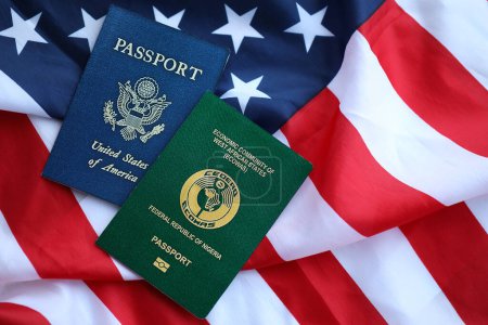 Téléchargez les photos : Passeport du Nigeria avec passeport américain sur drapeau plié des États-Unis d'Amérique gros plan - en image libre de droit