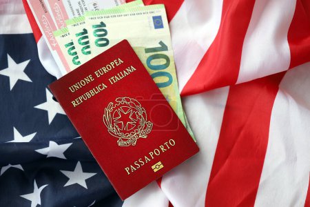Italian passport and money on United States national flag background close up. Tourism and diplomacy concept