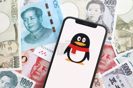 Téléchargez les photos : KYIV, UKRAINE - 1 AVRIL 2024 Tencent icône QQ sur l'écran du smartphone sur de nombreuses factures d'argent asiatiques. Écran iPhone avec logo app avec yens japonais et billets de banque yuans chinois - en image libre de droit